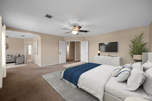 carpeted bedroom with ceiling fan and a textured ceiling