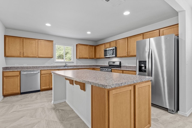 kitchen featuring a breakfast bar, a center island, stainless steel appliances, and sink