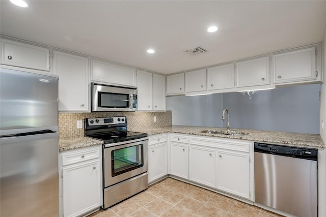 kitchen with visible vents, decorative backsplash, appliances with stainless steel finishes, white cabinetry, and a sink