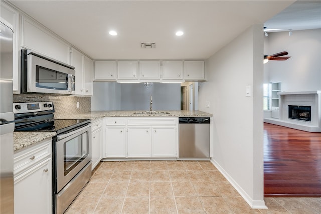 kitchen with sink, appliances with stainless steel finishes, white cabinetry, light stone counters, and decorative backsplash