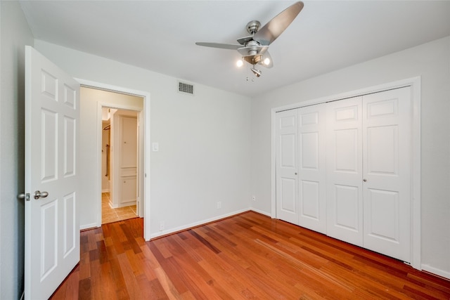 unfurnished bedroom featuring wood-type flooring, a closet, and ceiling fan