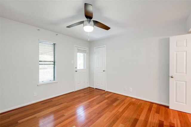 spare room featuring a ceiling fan, light wood-type flooring, and baseboards