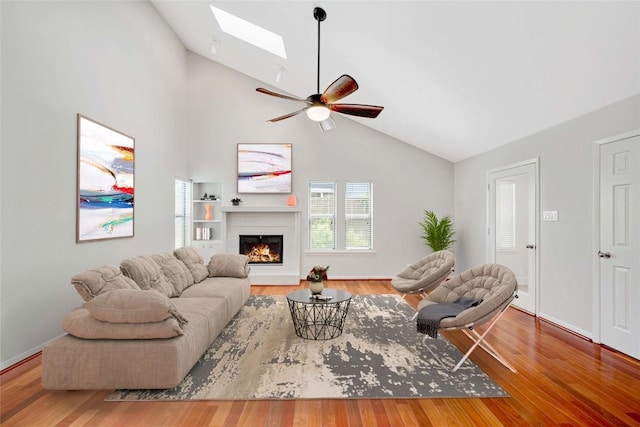 3315 W William Cannon Dr Unit A, Austin, TX 78745 - living room featuring vaulted ceiling, a skylight, a lit fireplace, wood finished floors, and ceiling fan