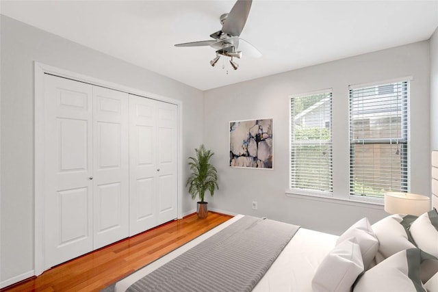 bedroom featuring a closet, ceiling fan, baseboards, and wood finished floors