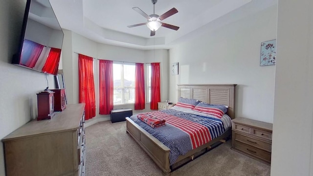 bedroom featuring carpet floors, a raised ceiling, and a ceiling fan