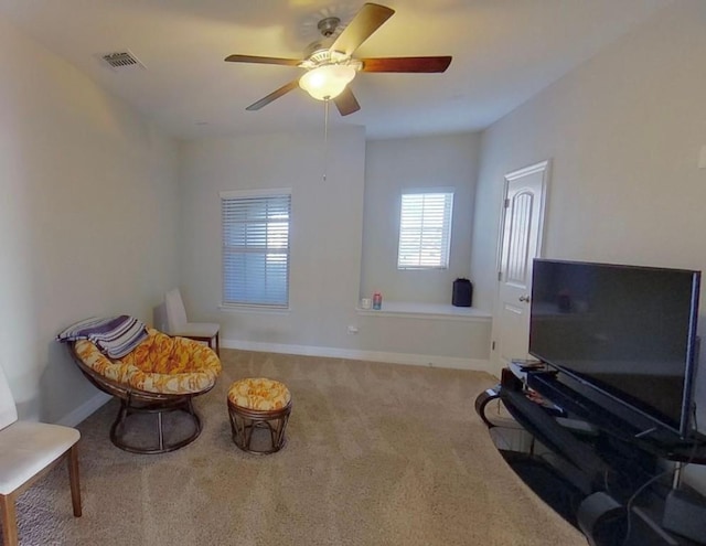 living area featuring carpet floors, visible vents, baseboards, and a ceiling fan