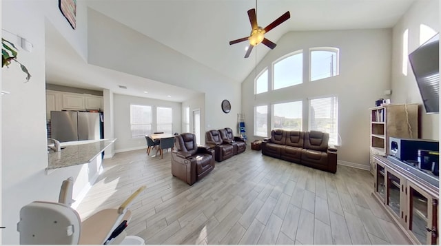 living room featuring high vaulted ceiling, ceiling fan, and light wood-type flooring