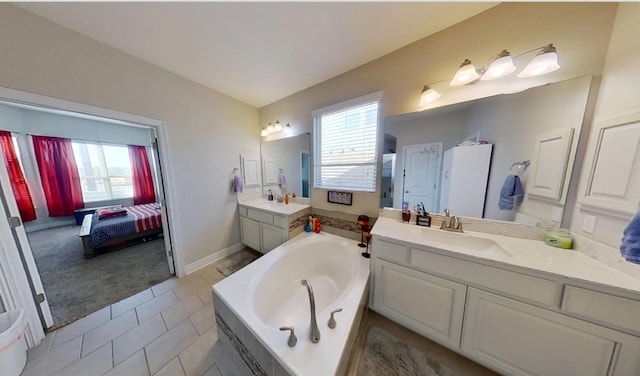 ensuite bathroom with a garden tub, plenty of natural light, two vanities, and a sink