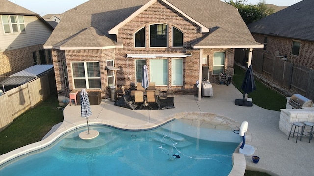 back of property featuring a patio area, a fenced backyard, roof with shingles, and brick siding