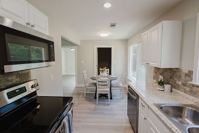 kitchen featuring white cabinets, appliances with stainless steel finishes, light wood-type flooring, and plenty of natural light