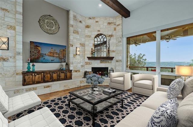 living room featuring a high ceiling, a fireplace, beam ceiling, hardwood / wood-style flooring, and ceiling fan