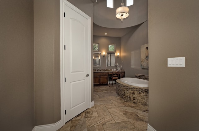 bathroom with tile patterned flooring, vanity, and a relaxing tiled tub