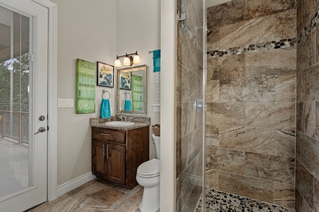 bathroom with toilet, a tile shower, vanity, and tile patterned floors