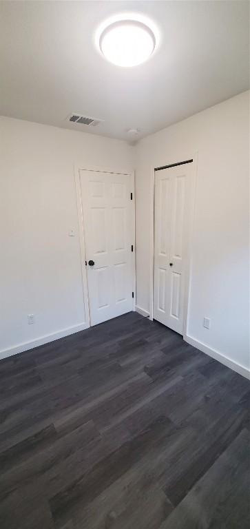 spare room featuring baseboards, visible vents, and dark wood-type flooring