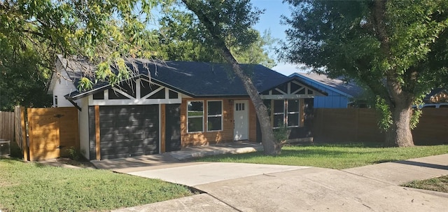 view of front of house featuring a garage, concrete driveway, a front lawn, and fence