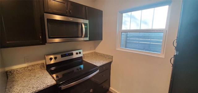 kitchen featuring dark brown cabinetry, appliances with stainless steel finishes, and light stone counters