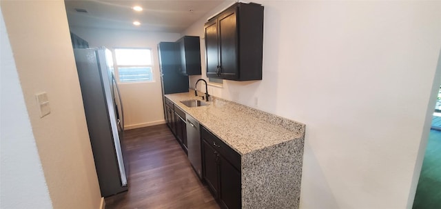 kitchen featuring light stone counters, recessed lighting, stainless steel appliances, dark wood-style flooring, and a sink