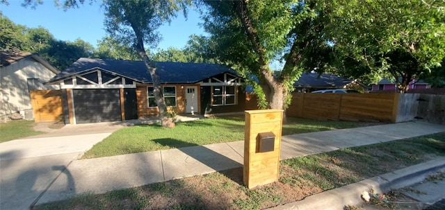 view of front facade featuring a garage, concrete driveway, a front lawn, and fence