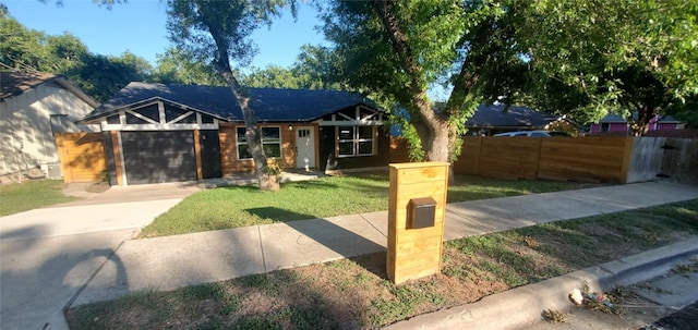 view of front facade with driveway, an attached garage, fence, and a front yard