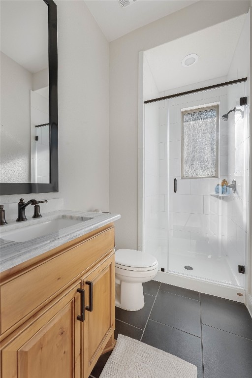 bathroom featuring vanity, a shower with shower door, toilet, and tile patterned flooring