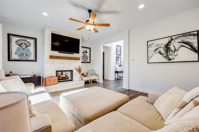 living room featuring dark wood-type flooring, a fireplace, and ceiling fan