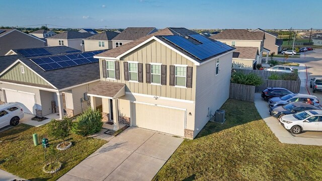 view of front facade with a garage, cooling unit, a front yard, and solar panels