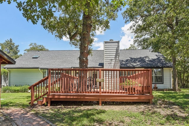 rear view of house with a wooden deck and a lawn