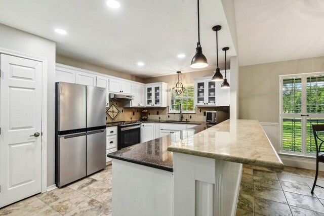 kitchen featuring decorative backsplash, stainless steel appliances, dark stone countertops, and light tile patterned floors