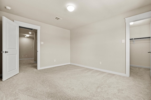 unfurnished bedroom with a walk in closet, light carpet, and a closet