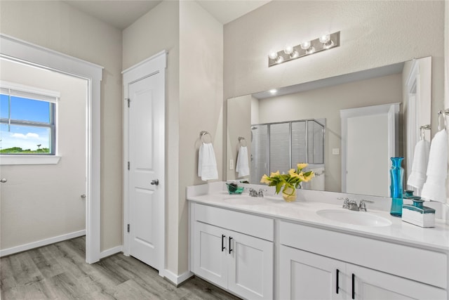 bathroom with hardwood / wood-style floors, vanity, and a shower with shower door