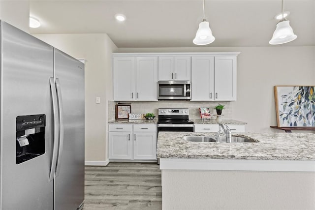 kitchen with hanging light fixtures, stainless steel appliances, light hardwood / wood-style flooring, backsplash, and white cabinets