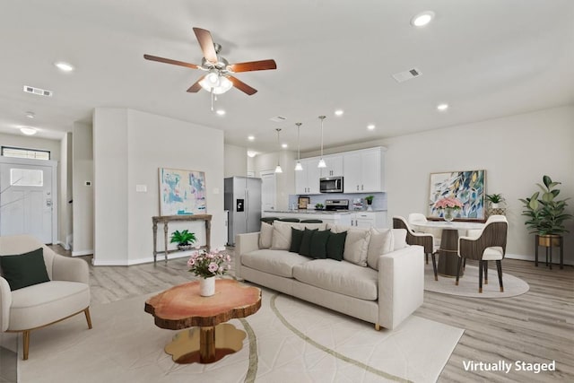 living room featuring ceiling fan and light wood-type flooring