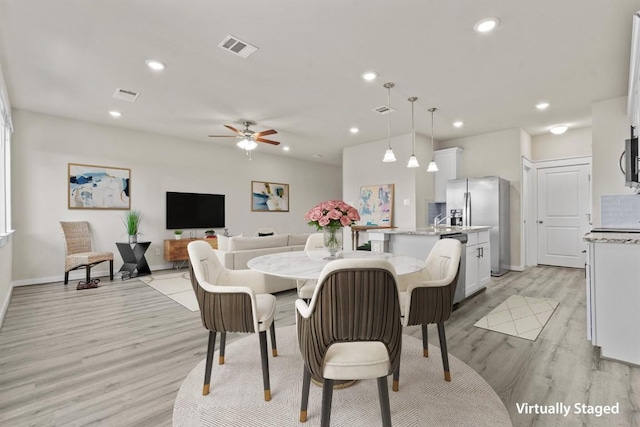 dining space with ceiling fan and light hardwood / wood-style flooring