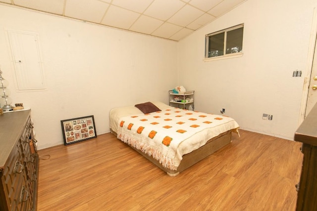 bedroom with light wood-type flooring, electric panel, and a drop ceiling