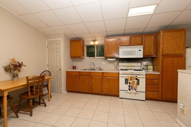 kitchen featuring brown cabinets, white appliances, light countertops, and a sink