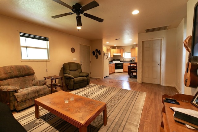 living room with light wood finished floors, baseboards, visible vents, a ceiling fan, and recessed lighting