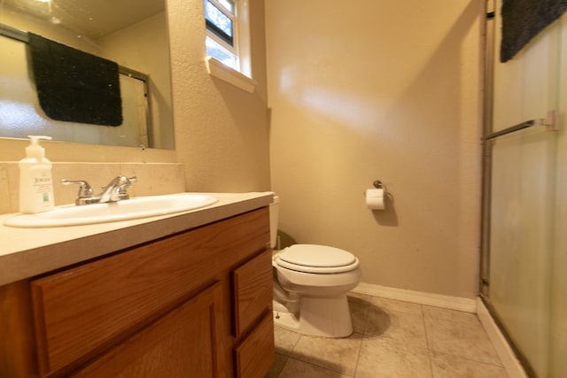 bathroom with a shower with shower door, vanity, tile patterned floors, and toilet