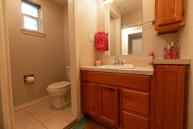 bathroom with toilet, vanity, baseboards, and tile patterned floors