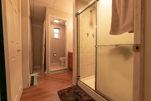 full bath with toilet, a shower stall, a closet, and wood finished floors