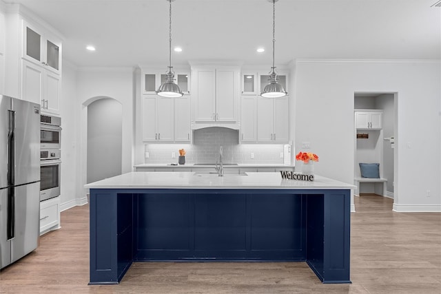 kitchen with crown molding, tasteful backsplash, light wood-type flooring, white cabinets, and stainless steel appliances