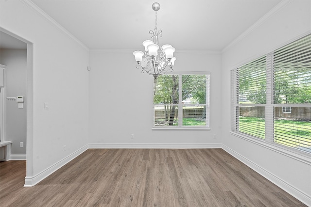 empty room featuring a notable chandelier, crown molding, and hardwood / wood-style floors