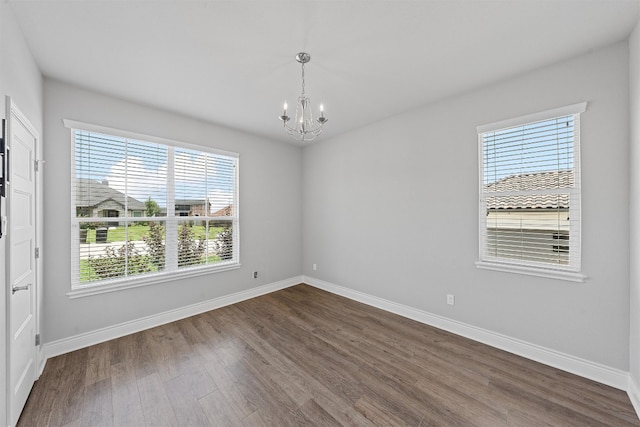 spare room with an inviting chandelier and hardwood / wood-style flooring