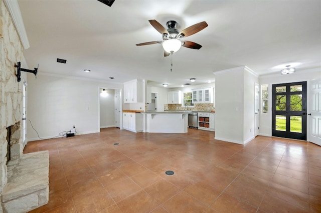 unfurnished living room with light tile patterned flooring, crown molding, a barn door, and ceiling fan