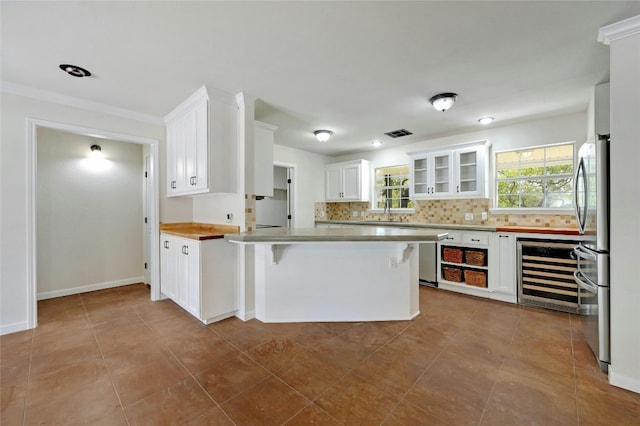 kitchen featuring white cabinets, beverage cooler, light tile patterned flooring, and decorative backsplash