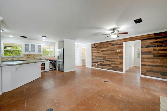 unfurnished living room featuring light tile patterned flooring, wood walls, and ceiling fan