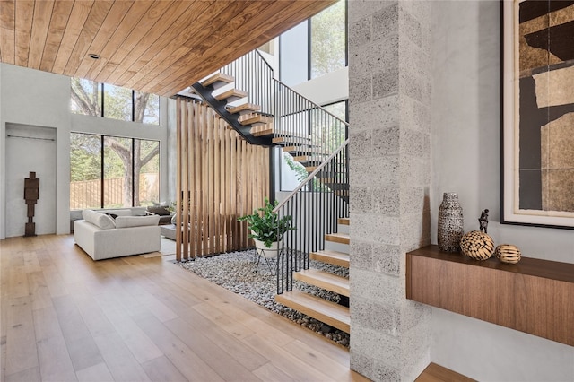 stairs with hardwood / wood-style flooring, wooden ceiling, and a towering ceiling