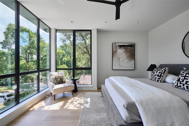 bedroom with multiple windows, ceiling fan, light hardwood / wood-style flooring, and floor to ceiling windows