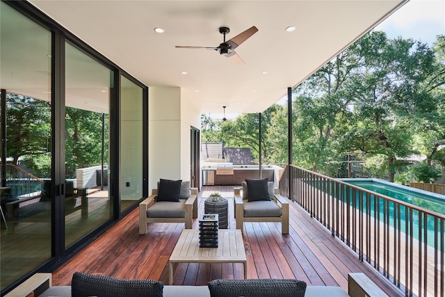 wooden terrace with outdoor lounge area, an outdoor kitchen, a fenced in pool, and ceiling fan