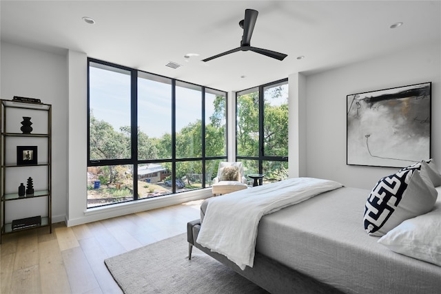 bedroom featuring ceiling fan, light hardwood / wood-style floors, and expansive windows