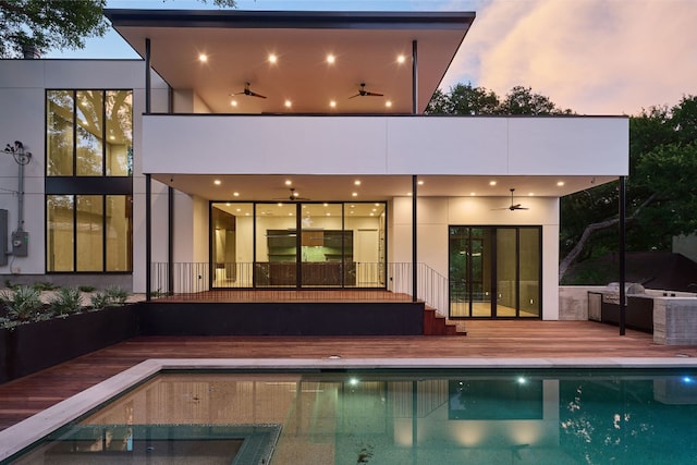 back house at dusk with ceiling fan, a fenced in pool, and a patio